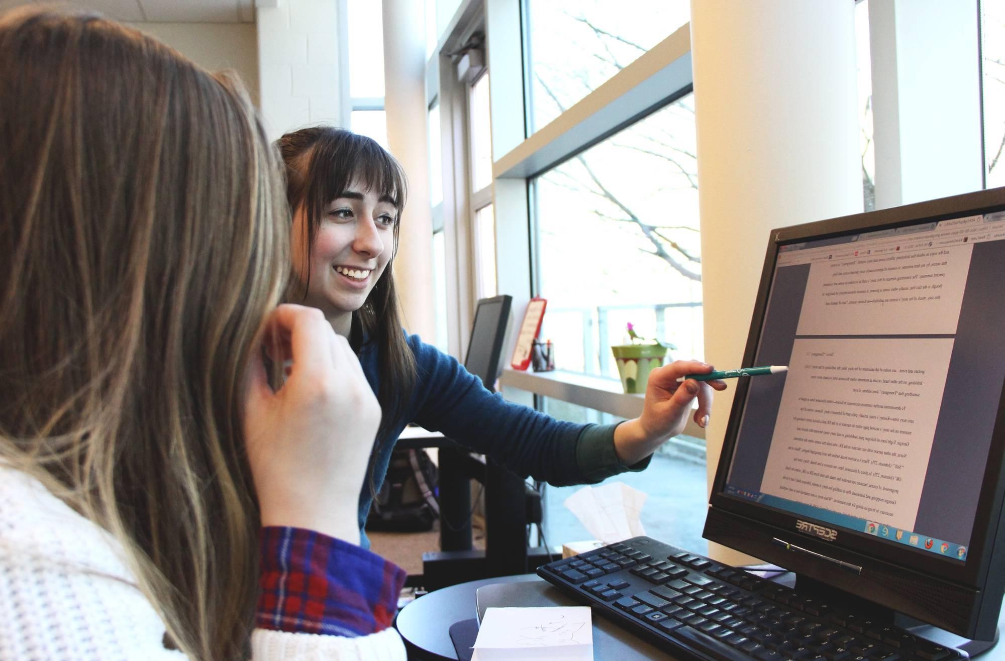 A student and a writing consultant working together at a computer